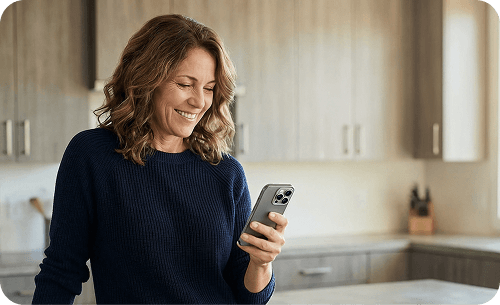 Frau hält Smartphone in der Hand und steht in der Küche