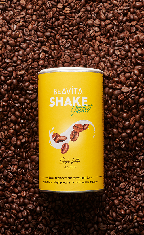 BEAVITA Diät-Shake mit Caffè-Latte-Geschmack und Kaffeebohnen im Hintergrund