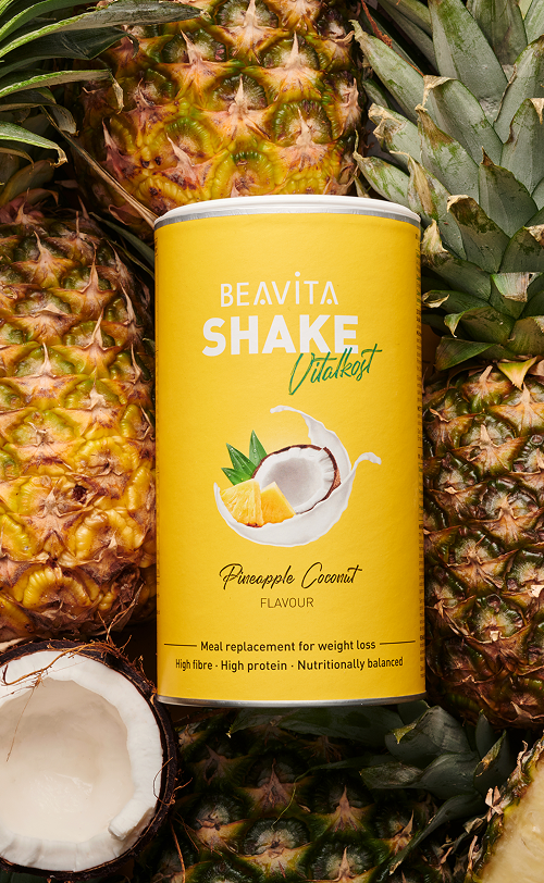 BEAVITA Diät-Shake mit Kokos-Ananas-Geschmack plus frischer Ananas und Kokosnuss im Hintergrund