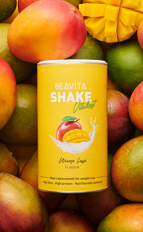 BEAVITA Diät-Shake mit Mango-Geschmack und frischen Mangos im Hintergrund