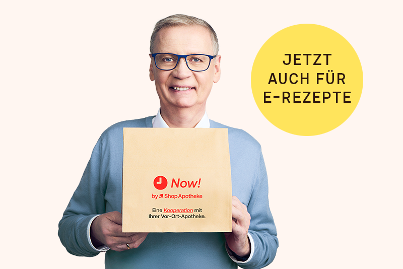 Eine lächelnde Frau sitzt im Garten und hält ein Paket von Shop Apotheke in der Hand.