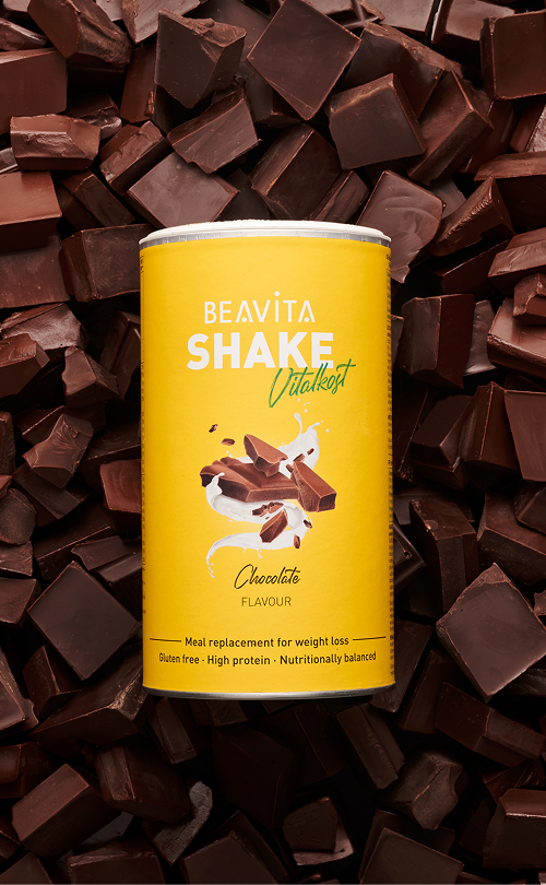BEAVITA Diät-Shake mit Schokoladen-Geschmack und Schokostückchen im Hintergrund