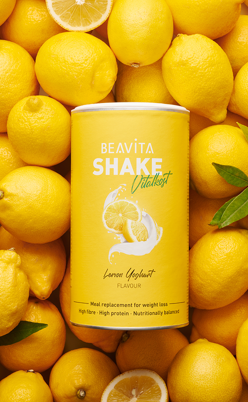 BEAVITA Diät-Shake mit Zitrone-Joghurt-Geschmack und frische Zitronen im Hintergrund