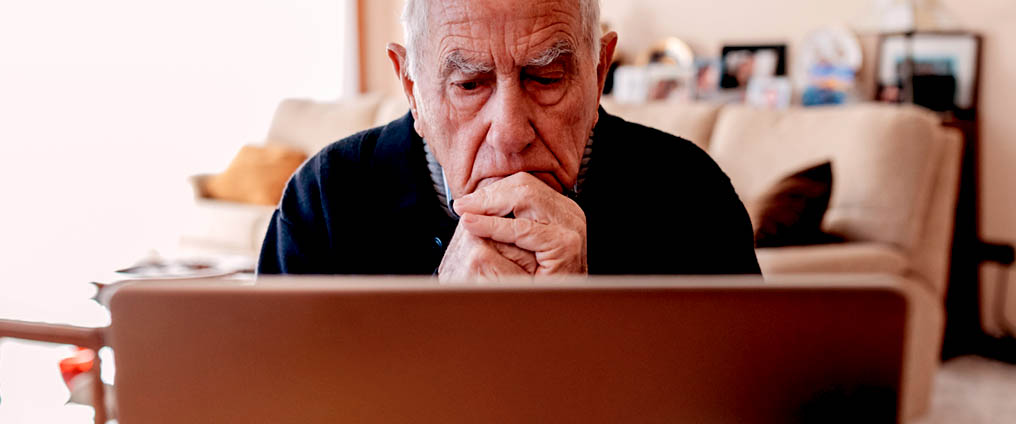 Senior sitzt vor Computer.