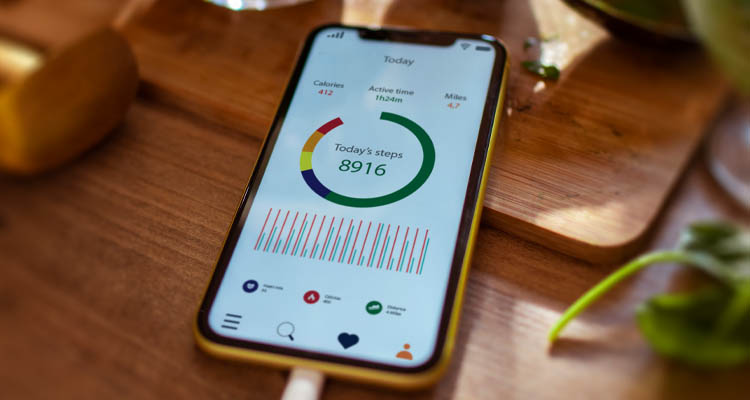 Ein Smartphone liegt auf einem Holztisch, die geöffnete App zeigt Tagesstatistiken mit 8.916 Schritten.