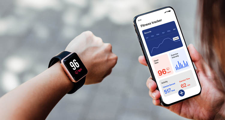 Eine Person trägt eine Smartwatch und bedient gleichzeitig eine Gesundheits-App auf dem Smartphone.