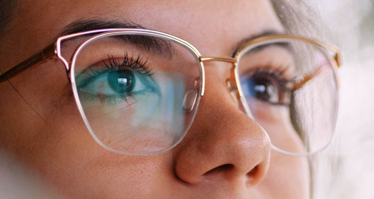 Brillenglas mit goldfarbenem Rahmen und runder Form, teilweise sichtbar auf der rechten Seite des Bildes.