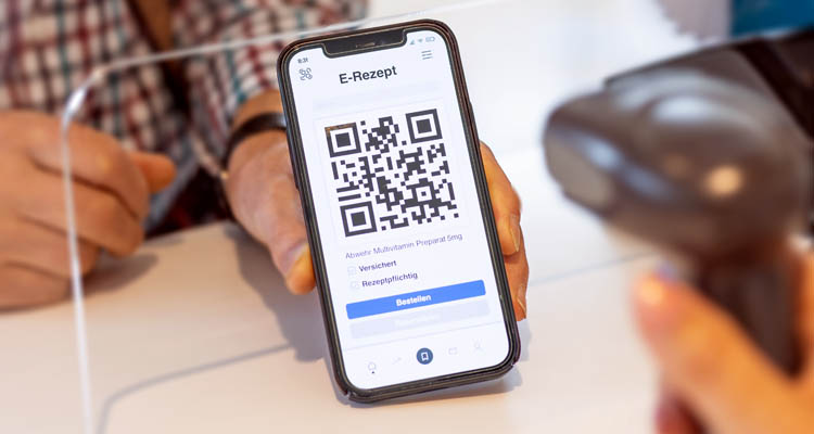 Hand hält Smartphone mit E-Rezept-App, zeigt QR-Code und Button 'Bestellen'. Eine andere Person scannt den Code.