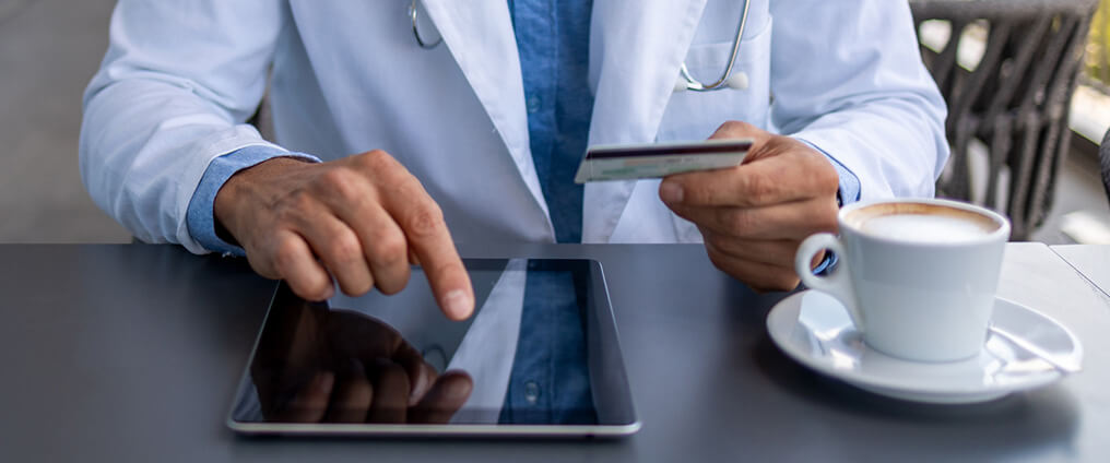 Arzt hält eHBA in der Hand und trägt Daten in ein Tablet.