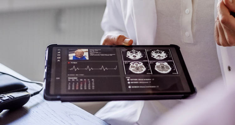 Arzt/Ärztin hält Tablet mit medizinischen Daten in der Hand.