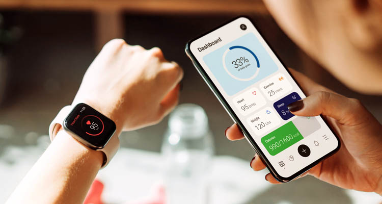 Eine Person trägt eine Smartwatch und bedient gleichzeitig eine Gesundheits-App auf dem Smartphone.