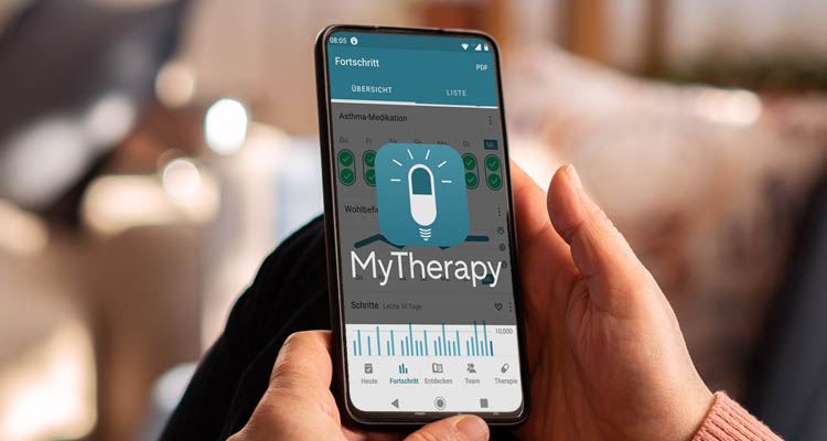 Eine Person hält ein Smartphone mit geöffneter MyTherapy-App, die Medikations- und Fortschrittsdaten anzeigt.