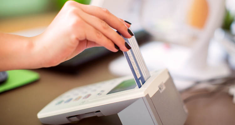 Eine Hand steckt eine Gesundheitskarte in ein Kartenlesegerät.