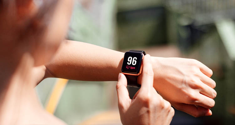Hand hält Smartphone mit Gesundheits-App, die Schritte, Kalorien und Aktivitätszeit anzeigt, im Hintergrund frisches Gemüse und Salat auf Holzbrett.