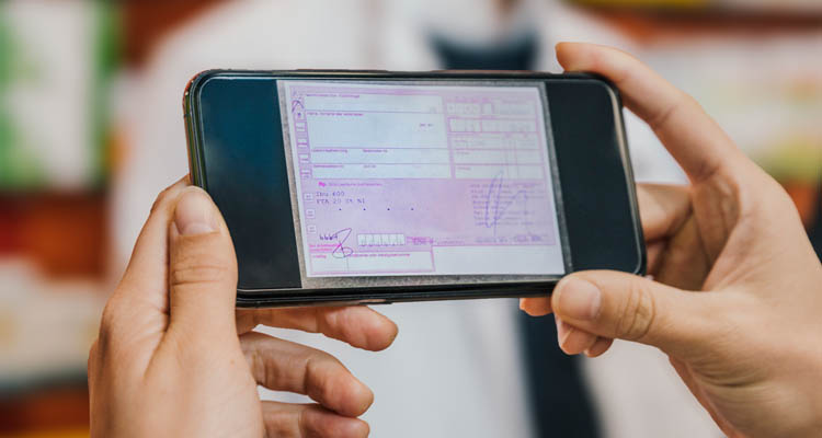 Hände halten ein Smartphone im Querformat, auf dem ein rosa Rezeptformular angezeigt wird.