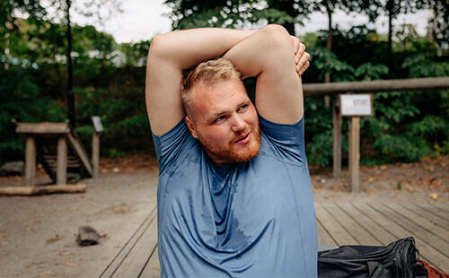 Junger Mann hat Sport getrieben und dehnt sich den Oberkörper.