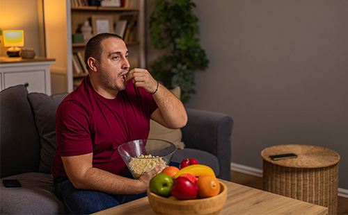 Ein Mann sitzt auf der Couch und isst Popcorn.