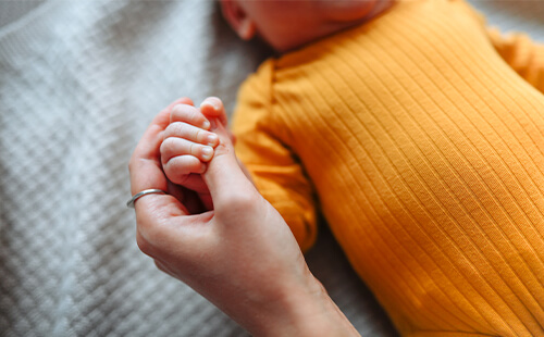 Eine Mutter hält die Hand ihres Säuglings. 