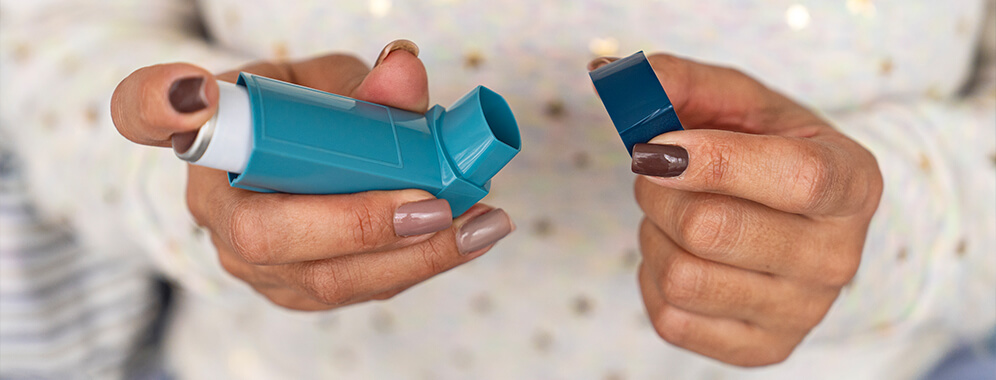 Frauenhände halten einen Inhalator.