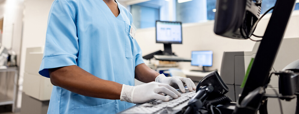 Eine Person steht in einem Labor am Computer und arbeitet.