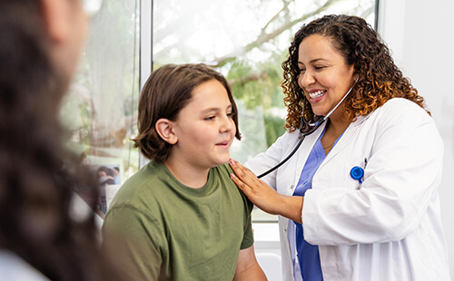 Ein kräftiges Kind wird in einer Arztpraxis abgehört. 