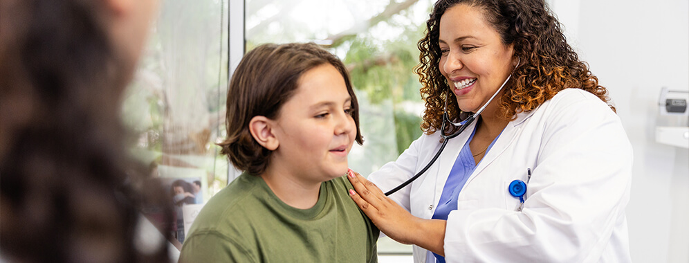 Ein kräftiges Kind wird in einer Arztpraxis abgehört.