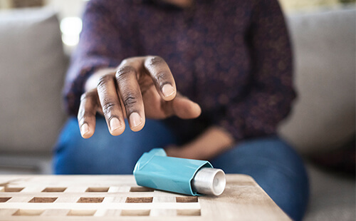 Eine Hand greift nach einem Inhalator.