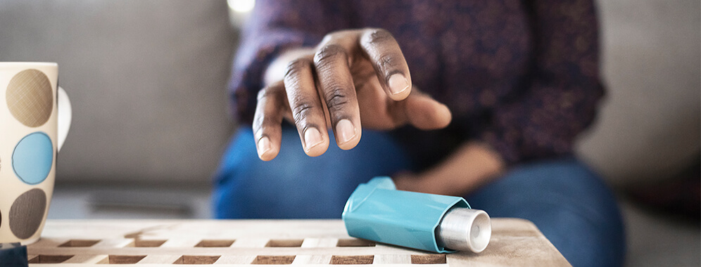 Eine Hand greift nach einem Inhalator.