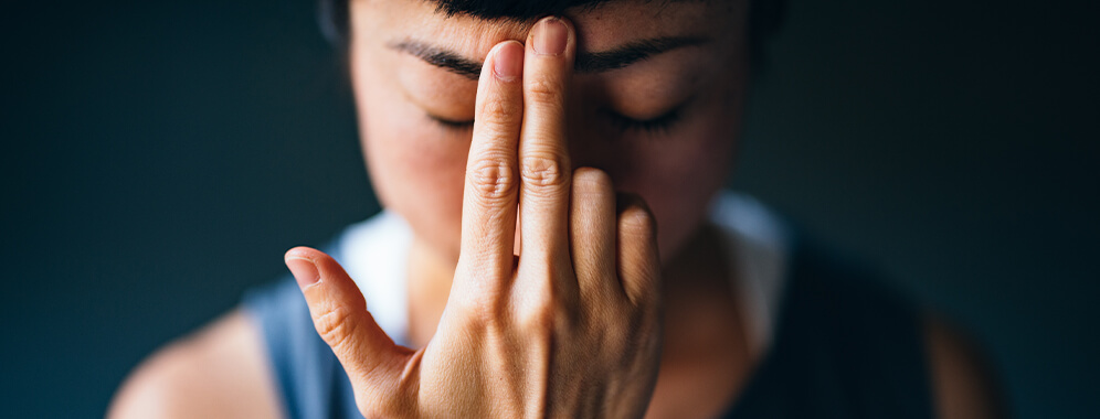 Eine Frau hält sich zwei Finger an die Stirn. 
