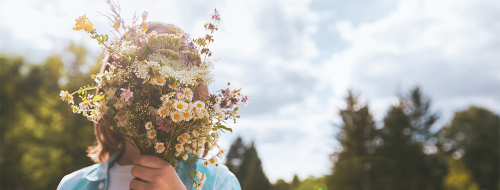 Eine Frau hält einen Blumenstrauß vor dem Gesicht.
