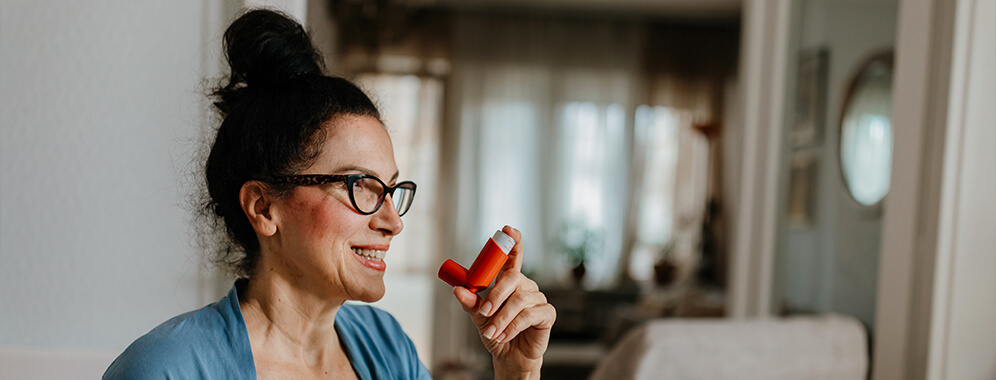 Eine Frau hält einen Inhalator in der Hand.