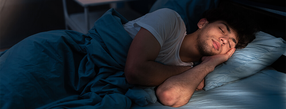 Ein Mann liegt im Bett und schläft. 