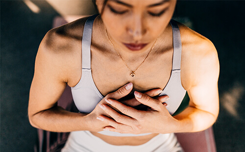 Eine Frau überkreuzt ihre Hände vor dem Brustkorb. 