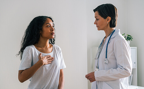 Eine Frau in einer Arztpraxis im Gespräch mit einer Ärztin. 