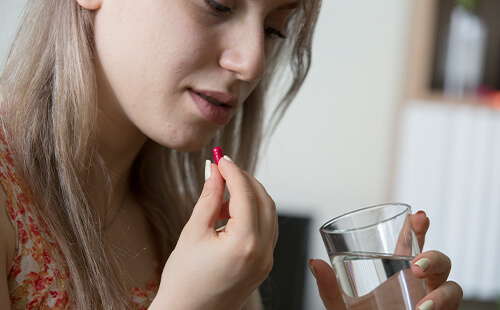 Eine Frau nimmt eine Pille ein. 
