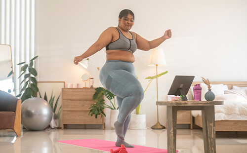 Eine übergewichtige Frau treibt zuhause Sport.