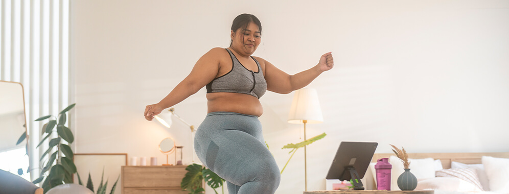 Eine übergewichtige Frau treibt zuhause Sport. 