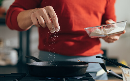 Ein Mann benutzt Salz beim Kochen. 