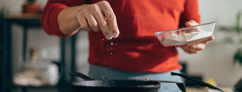 Ein Mann benutzt Salz beim Kochen.
