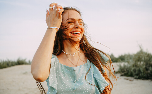 Eine lächelnde Frau mit Asthma steht draußen in leichtem Wind. 