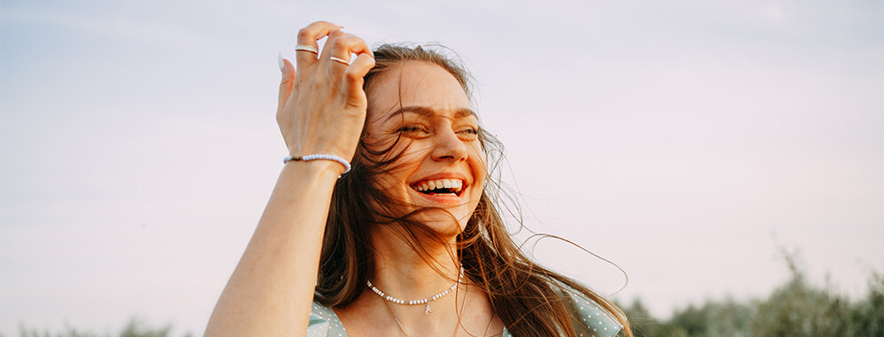 Eine lächelnde Frau mit Asthma steht draußen im leichten Wind. 