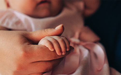 Eine erwachsene Hand hält die Hand eines Babys.