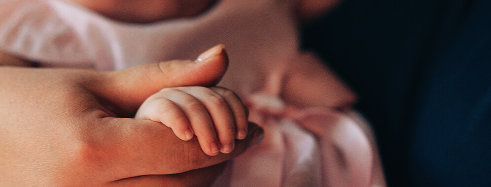 Eine erwachsene Hand hält die Hand eines Babys.