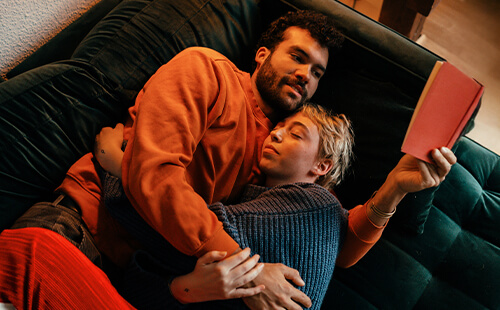 Ein Paar liegt zusammen auf dem Sofa. 