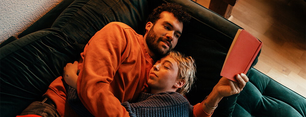 Ein Paar liegt zusammen auf dem Sofa. 