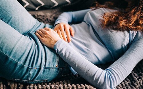 Eine Frau hält sich den Bauch. 