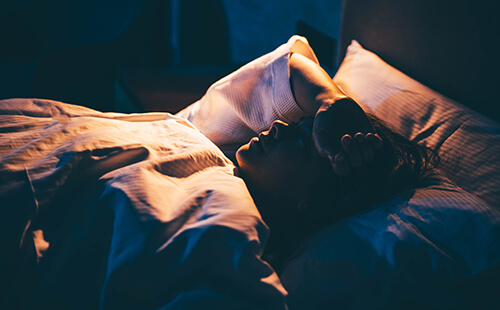 Eine Frau liegt im Bett und scheint nicht schlafen zu können. 