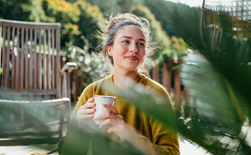 Eine Frau trinkt draußen einen Tee.