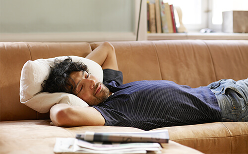 Ein Mann liegt erschöpft auf der Couch. 