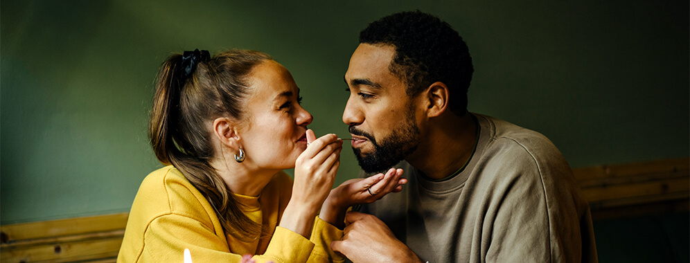 Eine Frau füttert spielerisch ihren Mann. 